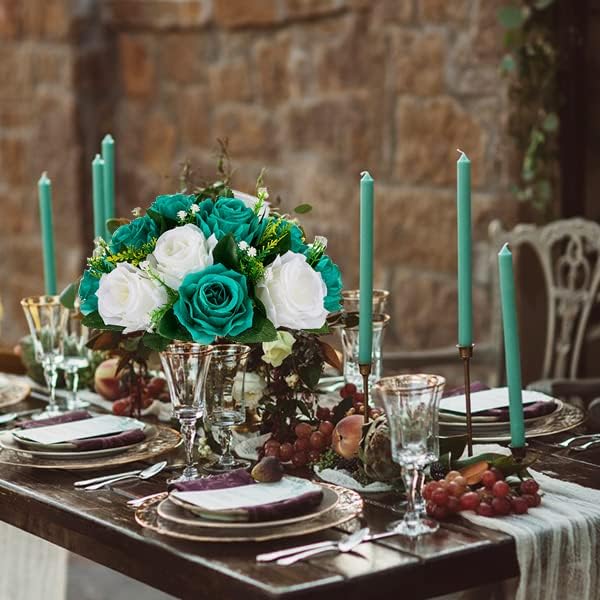 Elegant table setting with floral centerpiece, candles, and fine china against a stone wall.