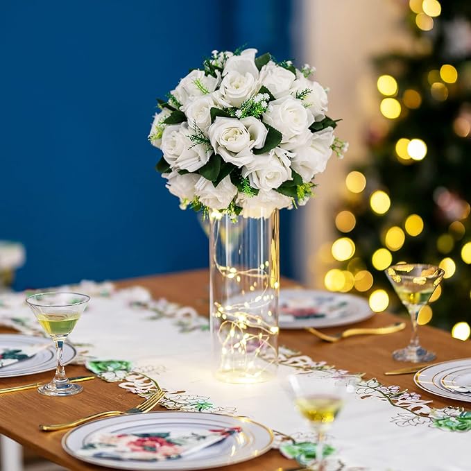 Decorative table setting with a vase of white flowers and Christmas tree in the background