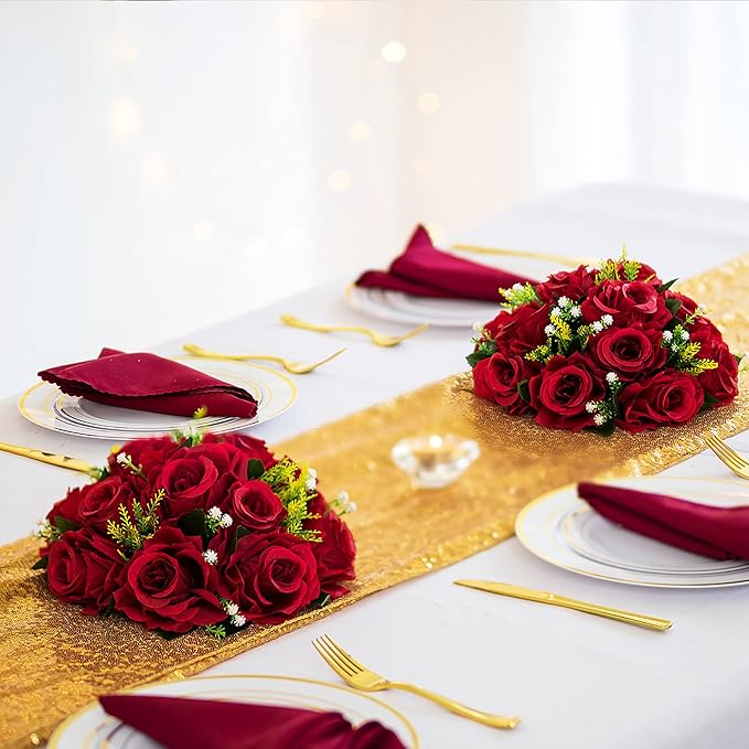 Decorative table setting with red roses, gold runner, and white plates.